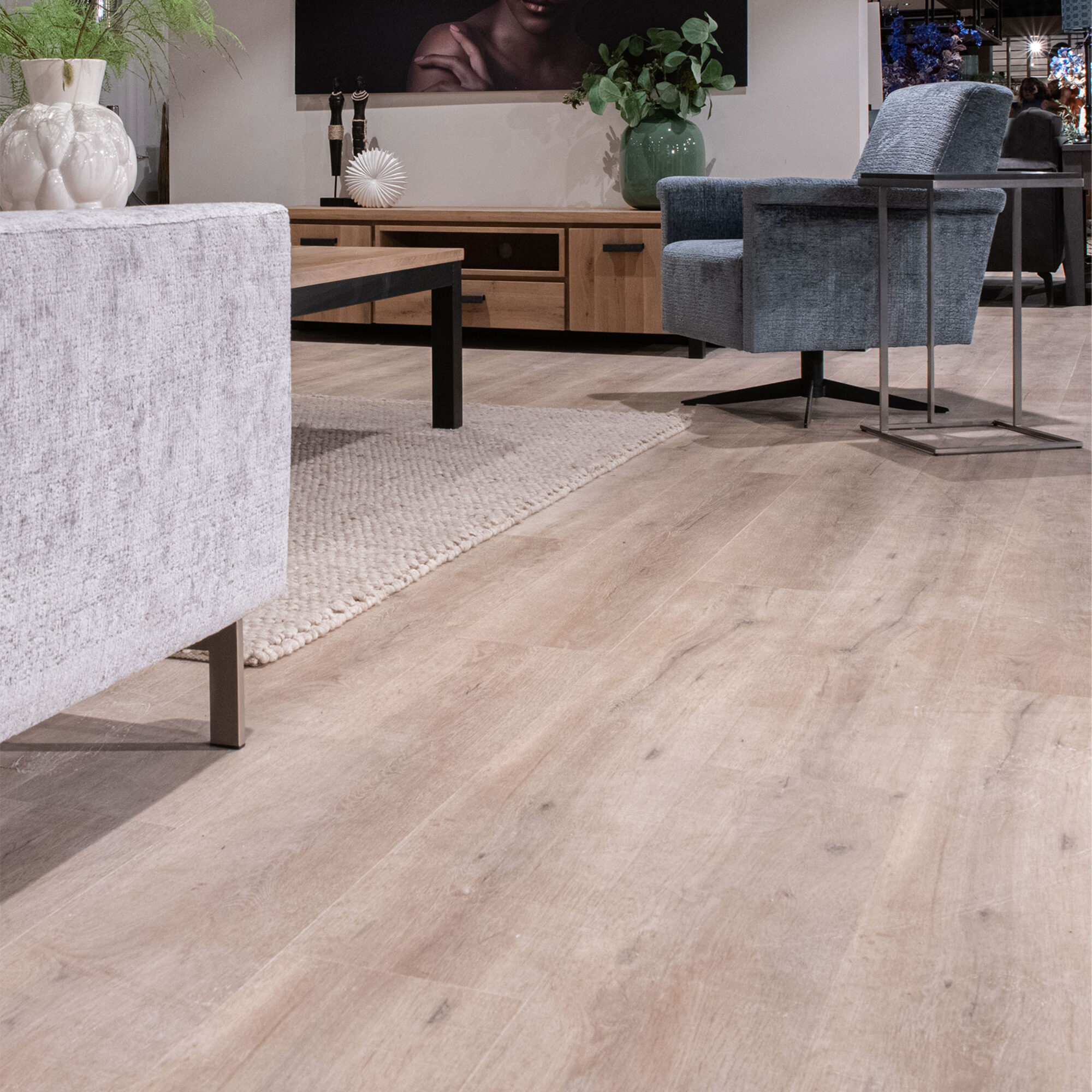 Lichte PVC-vloer in een modern interieur met een comfortabele stoel, een salontafel en een kunstwerk aan de muur.