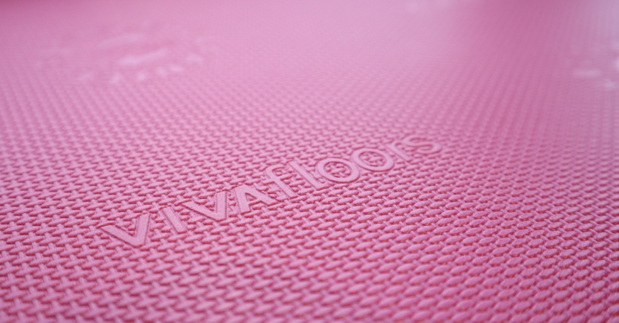 Close-up van een roze ondervloer voor een click-vloer, met het Vivafloors-logo in reliëf.