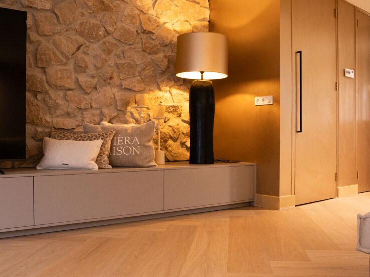 Lichte eiken PVC-vloer in een moderne woonkamer met een stenen muur, stijlvolle verlichting en een warme sfeer.