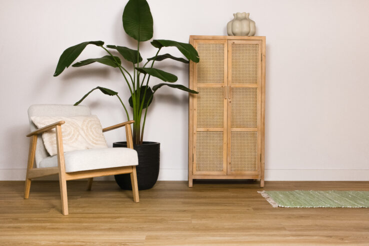 Lichte houten PVC-vloer in een gezellige interieursetting met een comfortabele stoel, een plant en een houten kast.