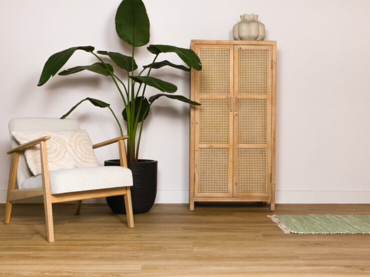 Lichte houten PVC-vloer in een gezellige interieursetting met een comfortabele stoel, een plant en een houten kast.