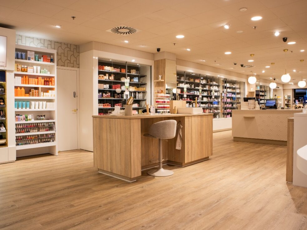 Lichte houten PVC-vloer in een commerciële ruimte met open planken en moderne verlichting.