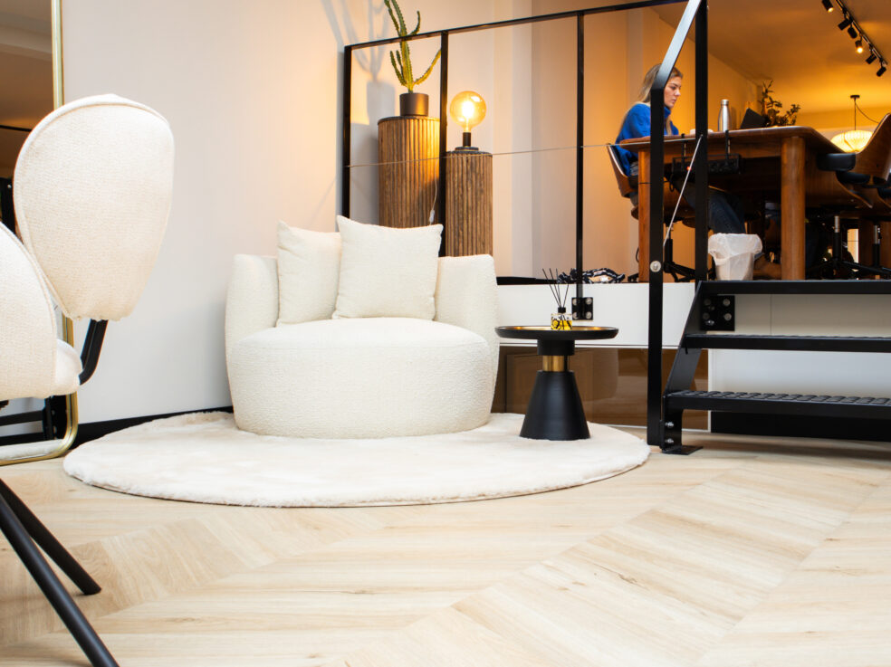 Lichte eiken PVC-vloer in een stijlvolle woonkamer met moderne meubels, een comfortabele zithoek en een open trap naar boven.