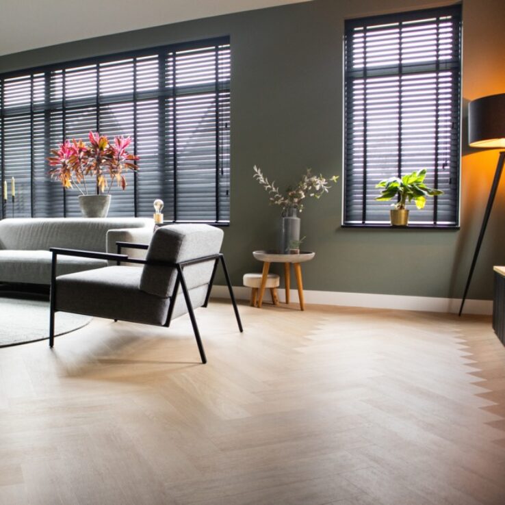 Lichte eiken PVC-vloer in een moderne woonkamer met een comfortabele bank, stijlvolle meubels en veel natuurlijk licht.