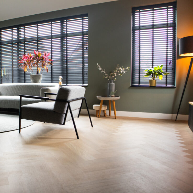 Lichte eiken PVC-vloer in een moderne woonkamer met een comfortabele bank, stijlvolle meubels en veel natuurlijk licht.