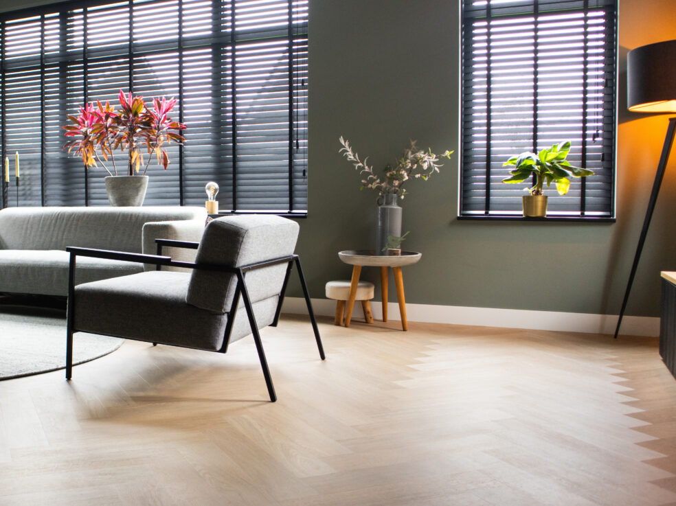 Lichte eiken PVC-vloer in een moderne woonkamer met een comfortabele bank, stijlvolle meubels en veel natuurlijk licht.