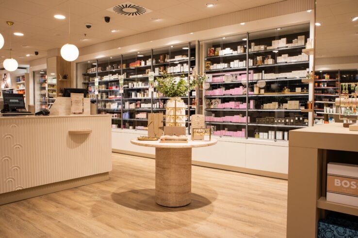 Lichte houten PVC-vloer in een moderne winkelruimte met schappen vol producten en een centraal display