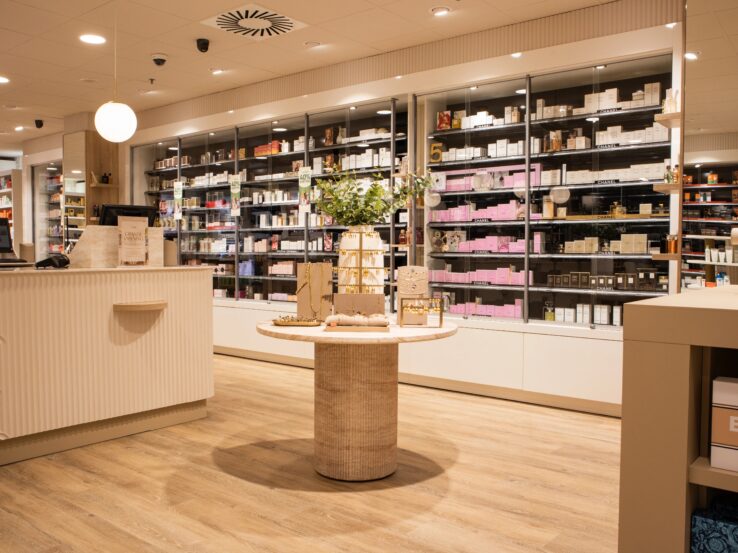 Lichte houten PVC-vloer in een moderne winkelruimte met schappen vol producten en een centraal display