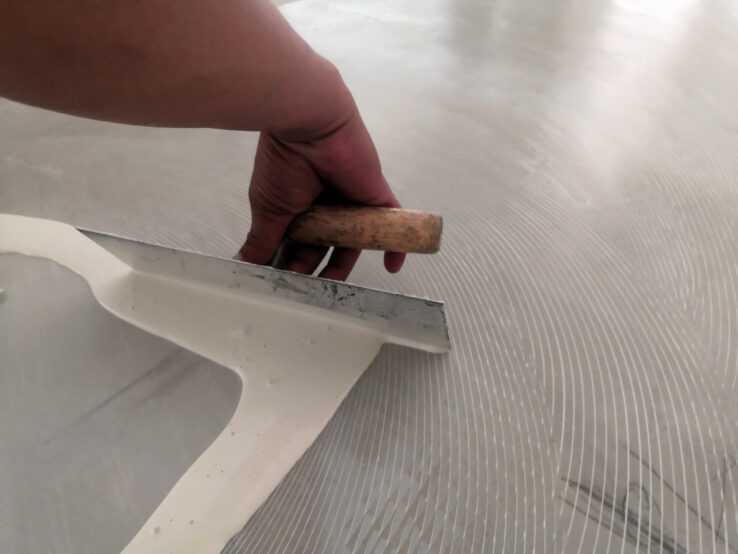 Iemand die een ondergrond aan het egaliseren is met egaline en een strijkstok