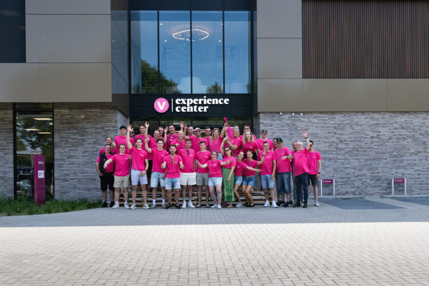 Groepsfoto van het Vivafloors team in roze shirts voor de ingang van het Experience Center
