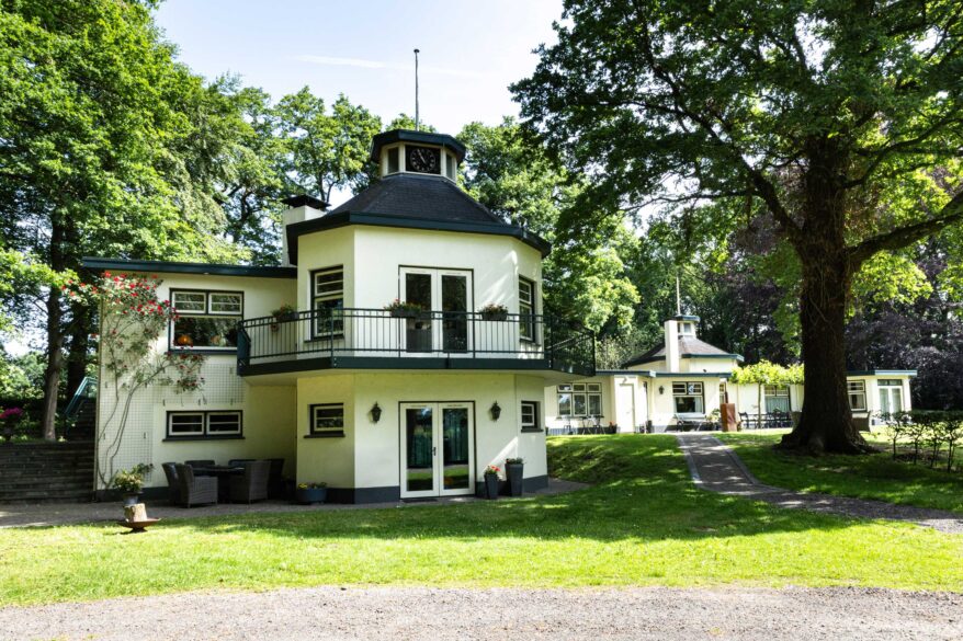 Wit achthoekig landhuis met torentje en balkon in een bosrijke tuin in Haaksbergen
