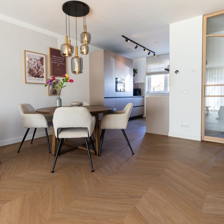 Eetkamer met ronde tafel, witte stoelen en glazen hanglampen op vloer Hongaarse punt 7880